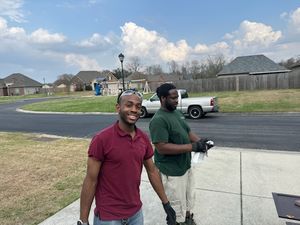Two men standing outdoors at a park with playground equipment and vehicles visible in background