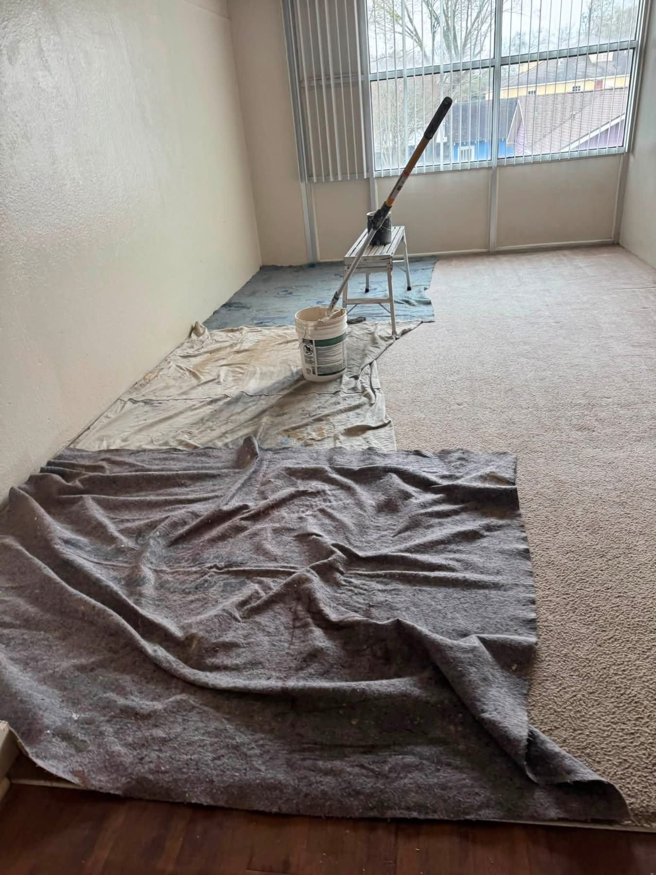 Paint bucket and brush on drop cloth in empty office room