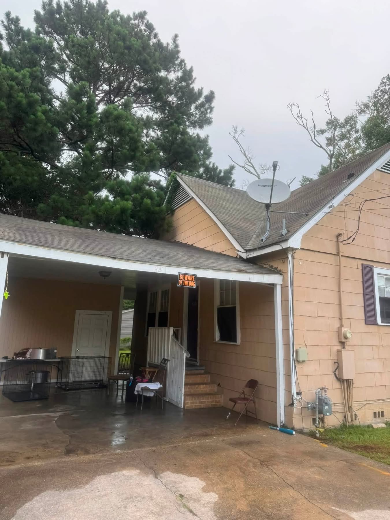 Single-story tan house with covered porch, satellite dish, and "Beware of Dog" sign