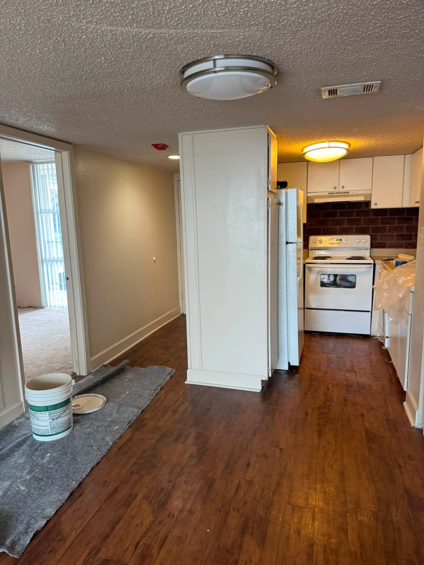 Kitchen renovation in progress with white cabinets, stainless appliances, and dark wood flooring