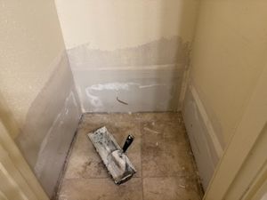 Empty room with plastic sheeting on walls and construction materials on floor