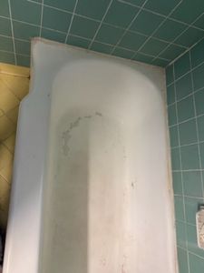White rectangular bathtub against tiled bathroom wall with green and yellow tiles