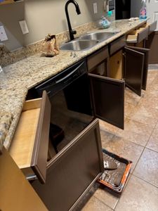 Kitchen cabinet with open doors revealing interior storage space and granite countertop