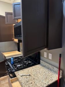 Kitchen renovation in progress with black cabinetry and granite countertop installation