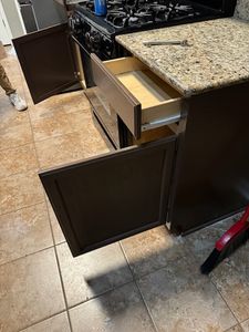 Dark kitchen cabinets with open drawers displaying storage organization