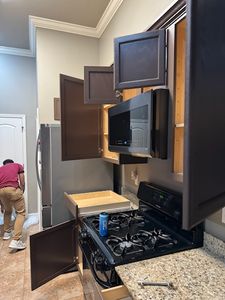 Modern kitchen appliance showroom display with open cabinet doors revealing stainless steel interior and black countertop